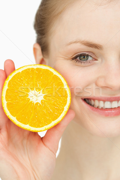 Close up of a smiling woman holding an orange against white background Stock photo © wavebreak_media