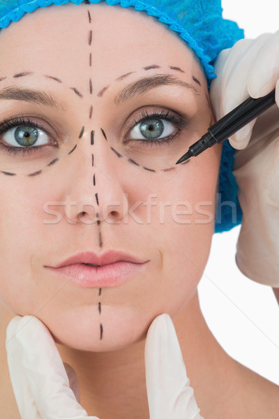 Stock photo: Doctor drawing on woman's face for face lift on white background