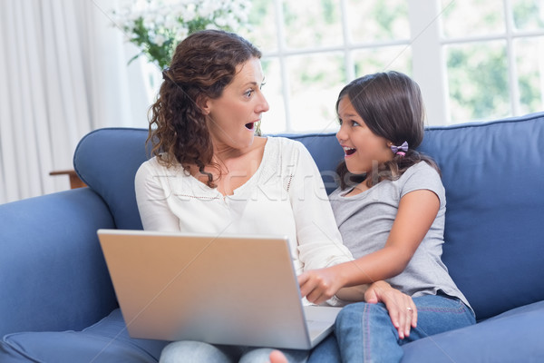 Happy mother and daughter sitting on the couch and using laptop Stock photo © wavebreak_media