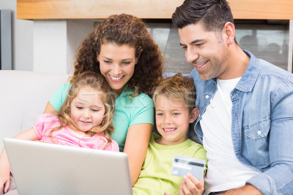 Famiglia felice seduta divano utilizzando il computer portatile insieme shop Foto d'archivio © wavebreak_media