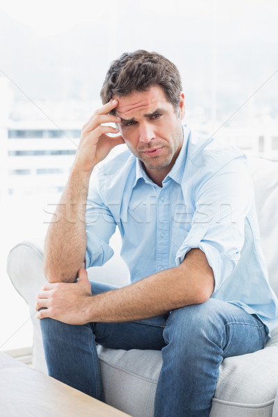 Stock photo: Man with headache sitting on the couch looking at camera