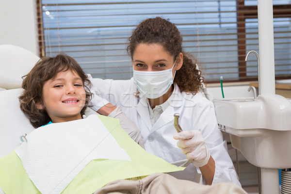 Stock photo: Pediatric dentist showing little boy in chair the drill