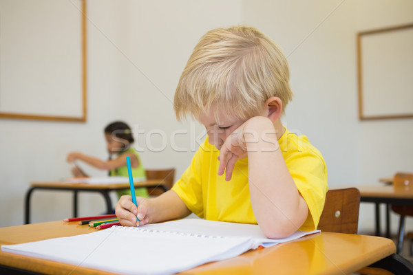 Stock photo: Cute pupils colouring at desks in classroom