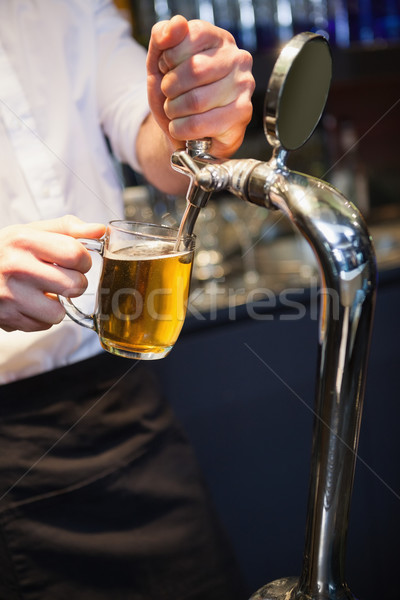 Handsome barkeeper pulling a pint of beer Stock photo © wavebreak_media