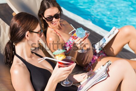 Stock photo: Smiling couple toasting drinks while relaxing on deck chairs at beach