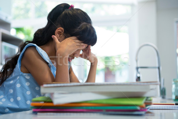 Side view of exhausted girl sitting by books in kitchen Stock photo © wavebreak_media