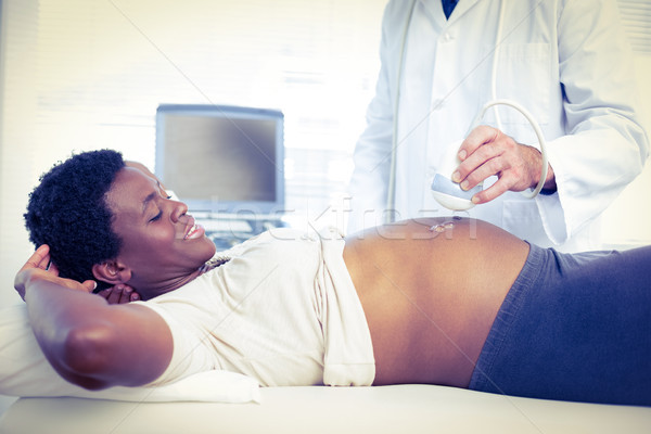 Stock photo: Male doctor performing ultrasound on smiling pregnant woman 