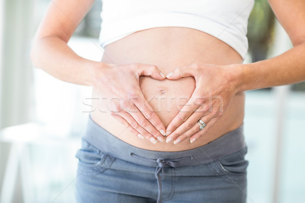 Midsection of woman hands making heart shape on belly Stock photo © wavebreak_media