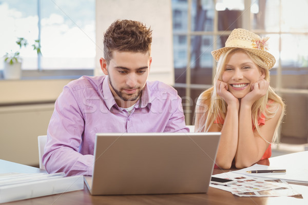 Business woman wearing hat sitting by male colleague Stock photo © wavebreak_media