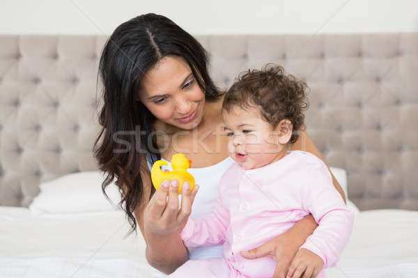 Happy brunette showing yellow duck to her baby Stock photo © wavebreak_media