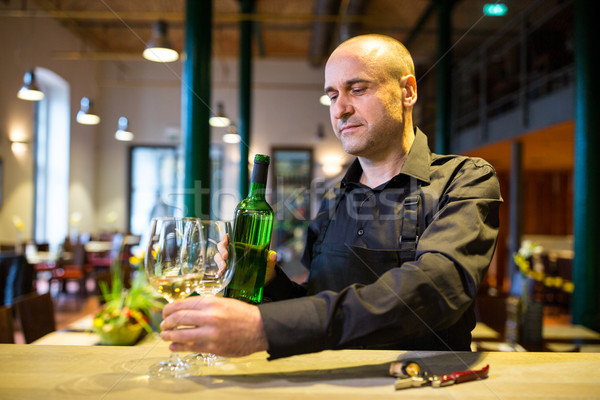 Waiter holding glasses and a bottle of white wine Stock photo © wavebreak_media