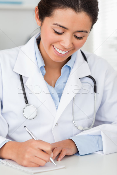 Charming female doctor writing on a scratchpad in her office Stock photo © wavebreak_media