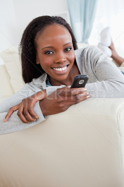 Stock photo: Close up of smiling woman texting on couch