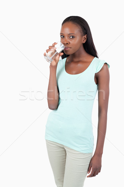 Stock photo: Young woman drinking a glass of water against a white background