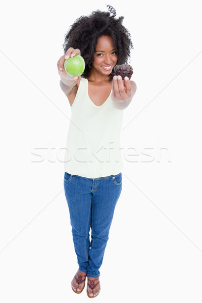 Smiling woman holding an apple in a hand and a muffin in the second one Stock photo © wavebreak_media