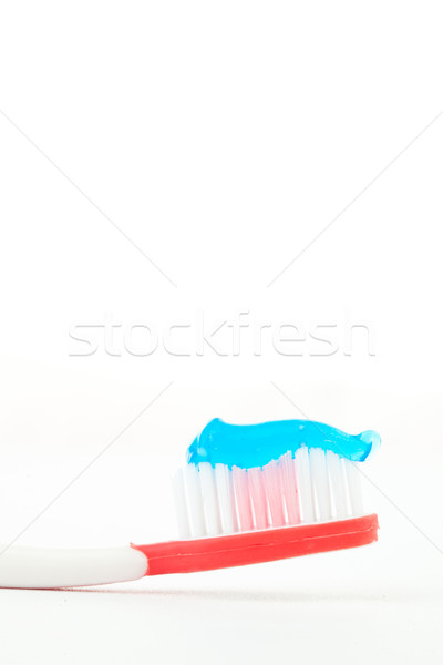 Blue toothpaste on a red toothbrush against white background Stock photo © wavebreak_media