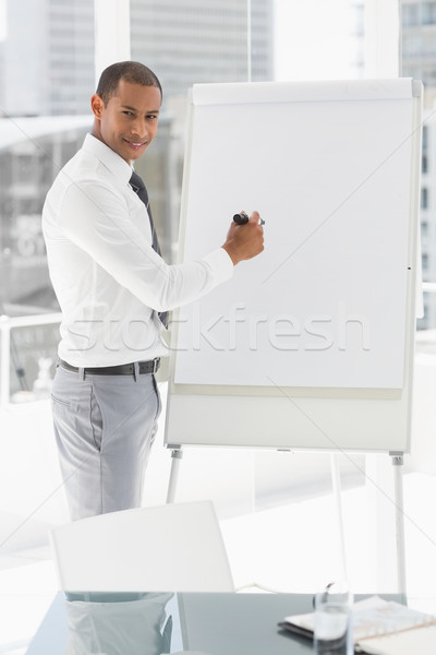 Young smiling businessman presenting at whiteboard with marker Stock photo © wavebreak_media
