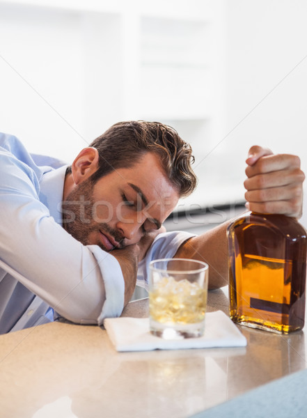 Drunk businessman clutching whiskey bottle asleep Stock photo © wavebreak_media