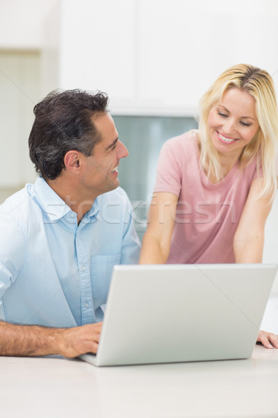 Stock photo: Happy couple using laptop in kitchen