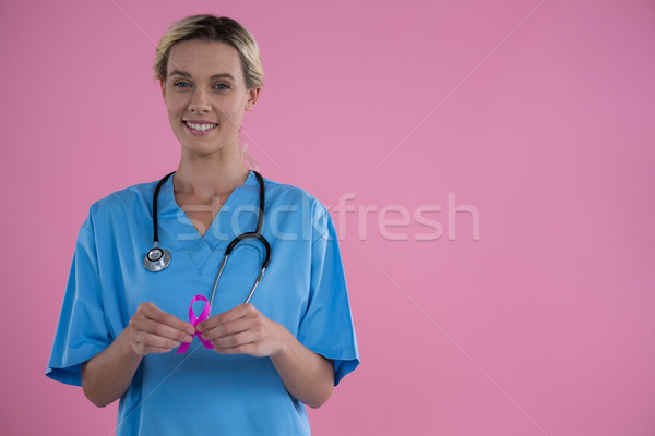 Portrait of smiling female doctor in scrubs showing Breast Cancer Awareness ribbon Stock photo © wavebreak_media