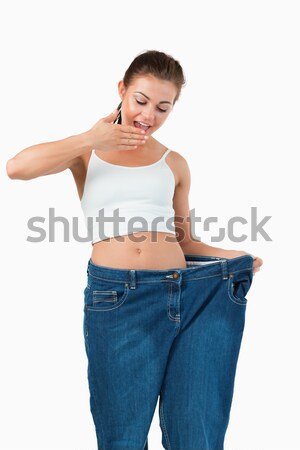 Smiling woman wearing to big jeans in a studio Stock photo © wavebreak_media