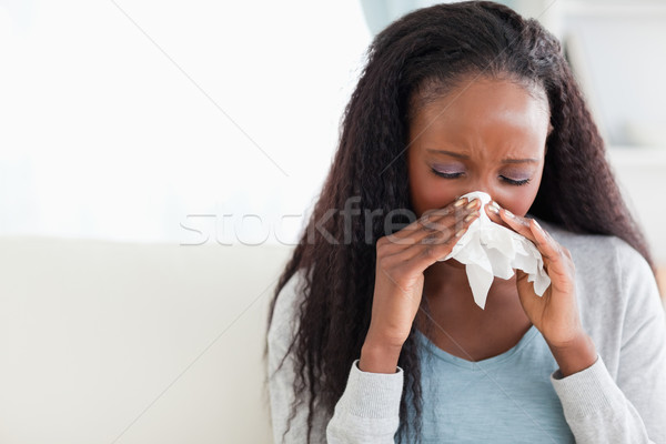 Close up of young woman blowing her nose on couch Stock photo © wavebreak_media