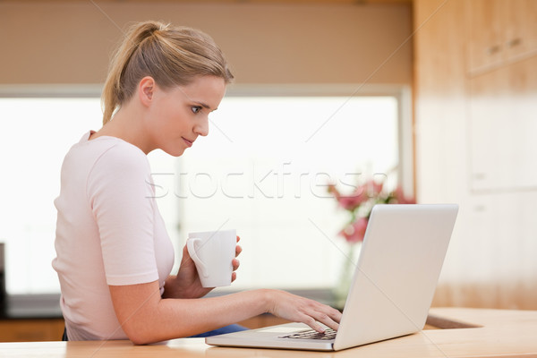 Mujer usando la computadora portátil potable taza té cocina Foto stock © wavebreak_media