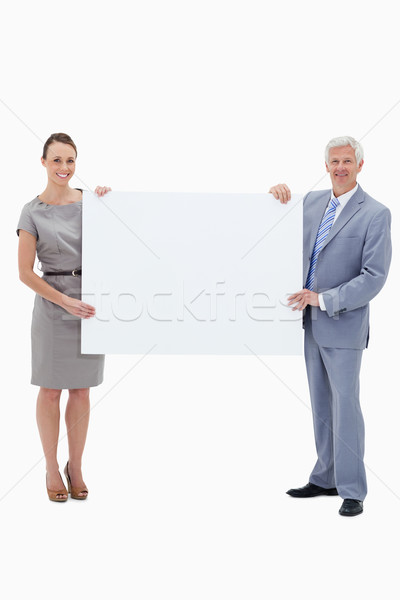 White hair businessman smiling and holding a big white sign with a woman against white background Stock photo © wavebreak_media