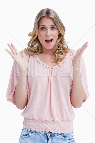 Stock photo: A surprised woman has her both arms held up in front of her against a white background