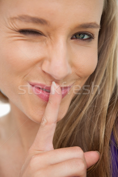 Green-eyes young woman winking with a finger on the lips against white background Stock photo © wavebreak_media