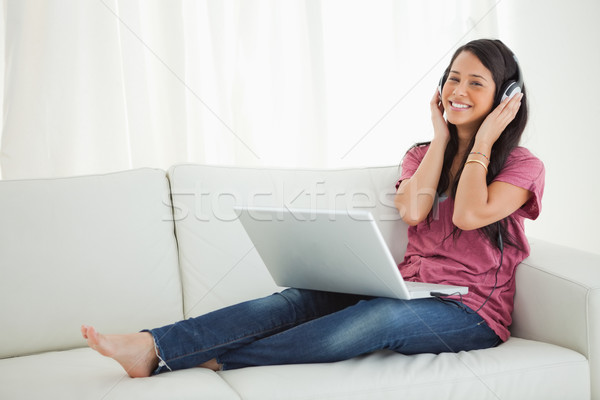 Smiling Latino student enjoying music on her sofa with a laptop on her knees Stock photo © wavebreak_media