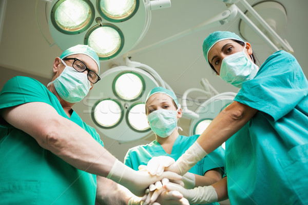 Surgical team joining hands in a surgical room Stock photo © wavebreak_media
