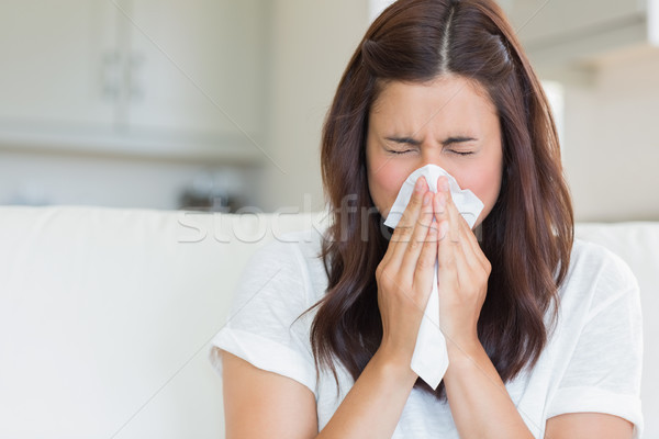 Brunette sneezing in a tissue in the living room Stock photo © wavebreak_media