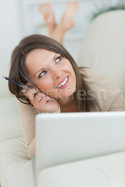 Nadenkend glimlachende vrouw met behulp van laptop sofa woonkamer computer Stockfoto © wavebreak_media