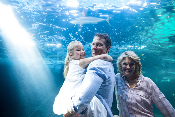 Happy family looking at camera behind a fish tank Stock photo © wavebreak_media