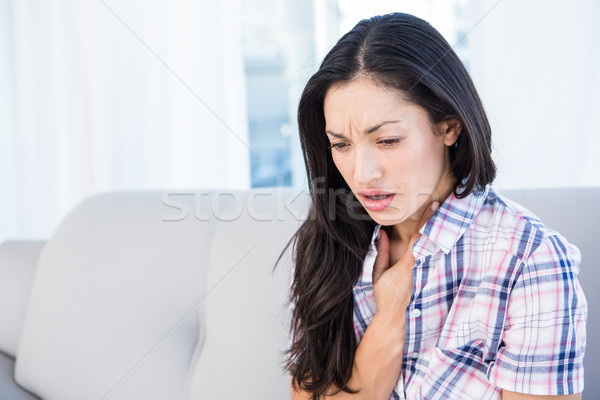Pretty brunette coughing on couch Stock photo © wavebreak_media