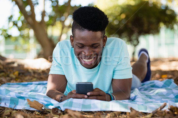 Stock photo: Young man using mobile phone while lying on a picnic blanket