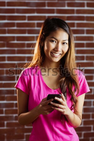 Mosolygó nő mobiltelefon téglafal nő telefon szépség Stock fotó © wavebreak_media