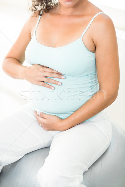 Pregnant woman sitting on exercise ball holding her belly Stock photo © wavebreak_media