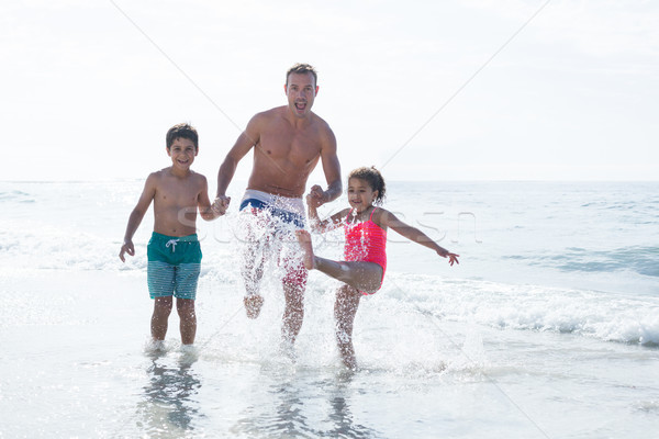 Cheerful father enjoying with children in shallow water Stock photo © wavebreak_media