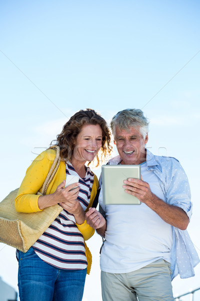 Stock photo: Happy couple using digital tablet against sky