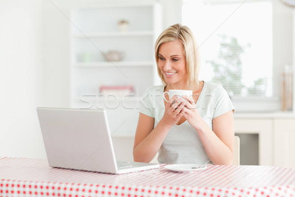 Woman holding coffee with laptop in front of her in the kitchen Stock photo © wavebreak_media