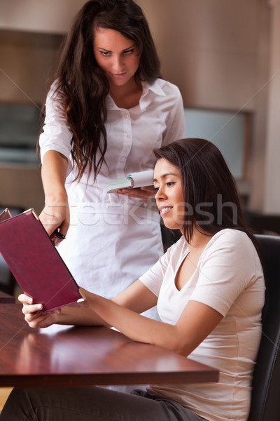 Portrait of a young waitress advising a customer pointing something on the menu Stock photo © wavebreak_media