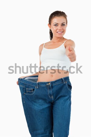 Portrait of a suprised woman wearing too large jeans against a white background Stock photo © wavebreak_media