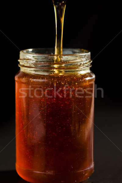 Honey trickle dropping in a honey jar against black background Stock photo © wavebreak_media