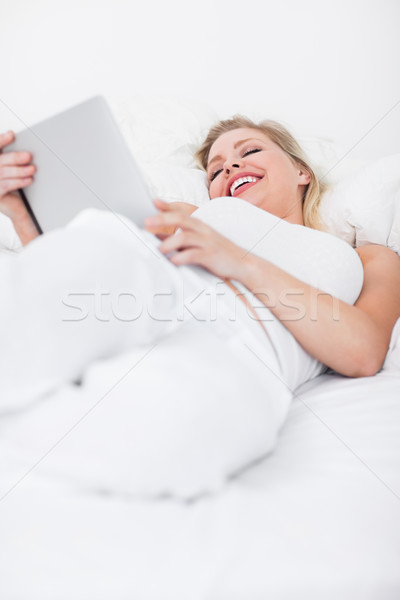 Foto stock: Riendo · ebook · lector · cama · lectura