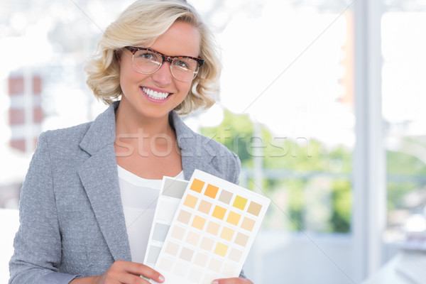 Stock photo: Pretty interior designer holding up colour samples