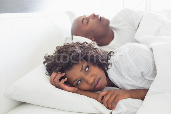 Annoyed woman lying in bed with snoring boyfriend Stock photo © wavebreak_media