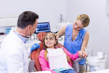 Pediatric dentist examining a little boys teeth with his mother Stock photo © wavebreak_media