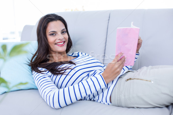 Sorridente belo morena relaxante sofá leitura Foto stock © wavebreak_media